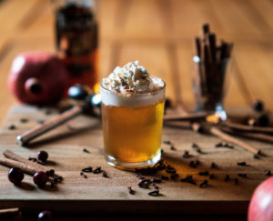 Apple Pie cocktail served in a rocks glass with whipped cream and spices.
