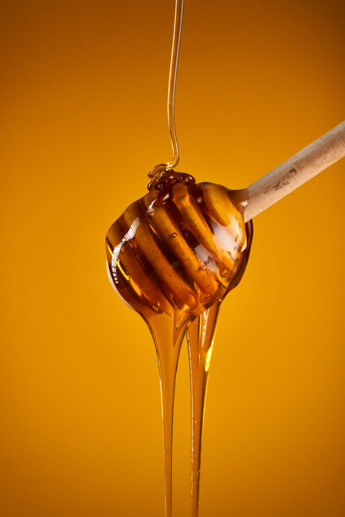 Honey dripping on wooden dipper